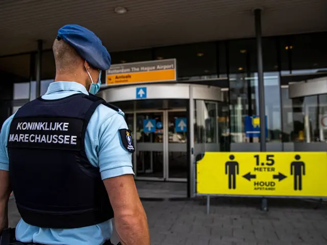 The image shows a police officer wearing a blue uniform and a blue cap standing in front of a...