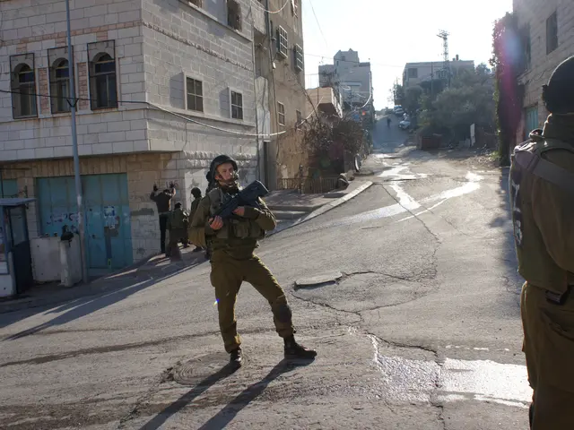 The image shows two Israeli soldiers standing guard in the West Bank city of Hebron. They are both...