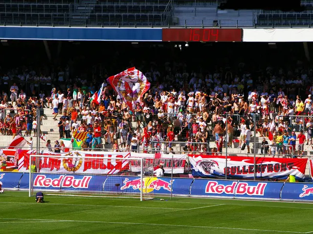 The image shows a soccer game being played in a stadium, with a group of people on the ground, a...