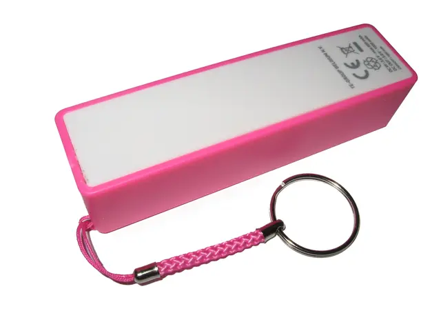 The image shows a pink power bank with a keychain attached to it, set against a white background.