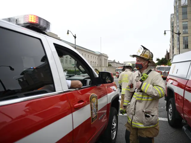 The image shows a group of firefighters standing next to a red and white truck on a city street....