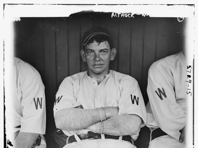 The image shows a black and white photo of three baseball players sitting in a dugout. The man in...