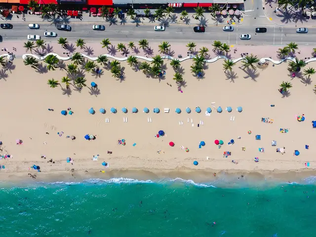 The image shows an aerial view of a beach in Miami, Florida, with people enjoying the sun and sand,...