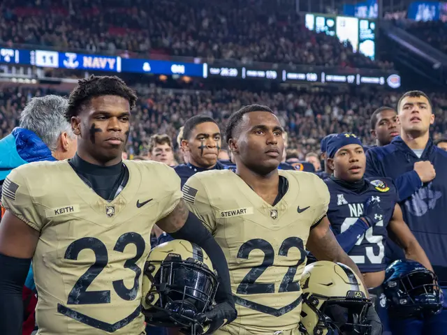 The image shows a group of men standing on top of a football field, wearing cream-colored uniforms...