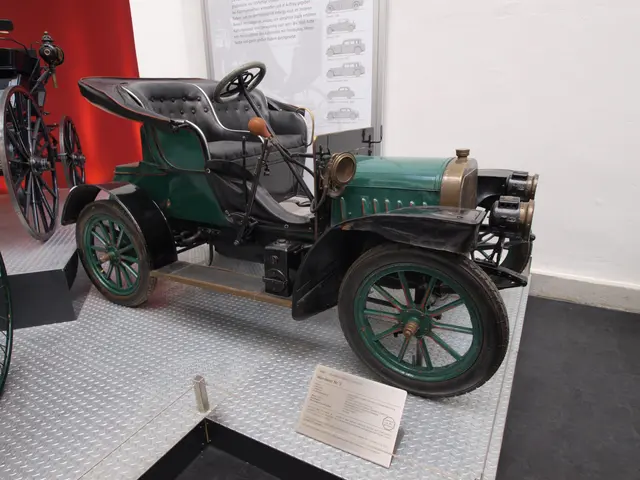 The image shows an old fashioned car on display in a museum, with a board with text in the...