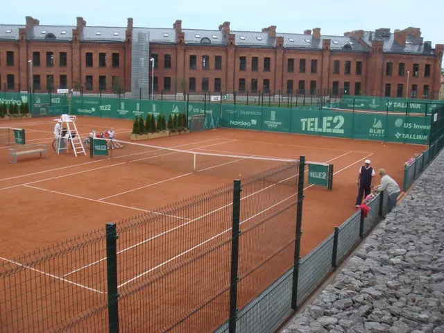 The image shows a group of people playing tennis on a clay court surrounded by a metal fence, with...