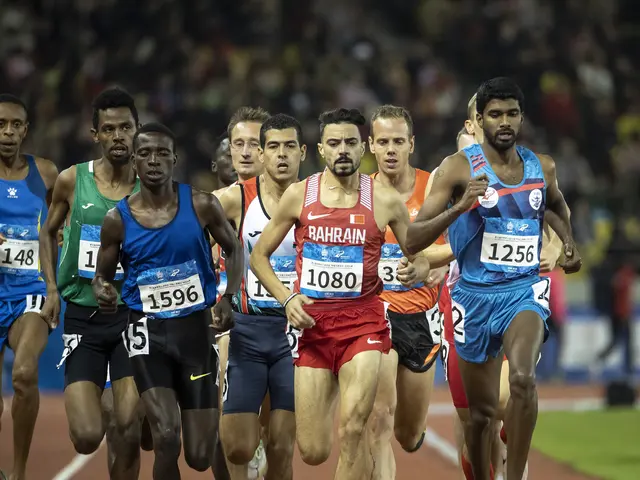 The image shows a group of men running on top of a track, with a blurred background. The men appear...