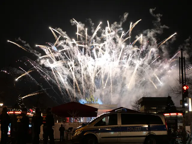 The image shows a police car parked in front of a crowd of people, illuminated by the lights of the...