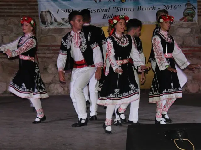 The image shows a group of people in traditional Bulgarian costumes dancing on a stage, with a...