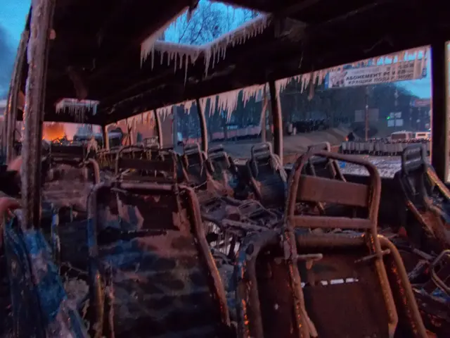 The image shows a bus that has been destroyed by a fire, with charred seats and icicles hanging...