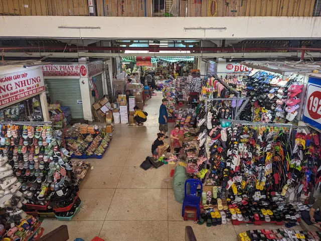 The image shows a bustling market in Ho Chi Minh City, Vietnam, with a variety of shoes for sale....