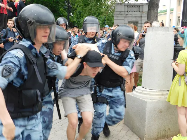 The image shows a group of people in riot gear running away from a crowd of people, some of whom...