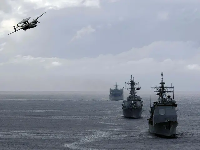 The image shows a drone flying over a group of ships in the ocean, with the sky in the background...