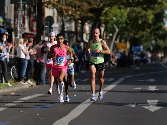 The image shows a group of people running in a marathon on a city street, with people standing on...