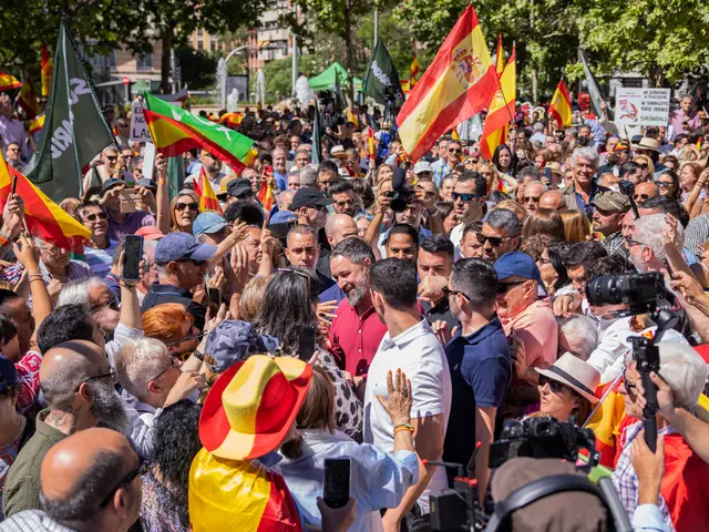 The image shows a large group of people standing in front of a crowd, some of them holding flags...