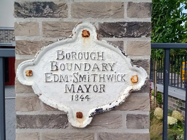 The image shows a stone plaque on the side of a building that reads "Borough Boundary Edm Smithwick...