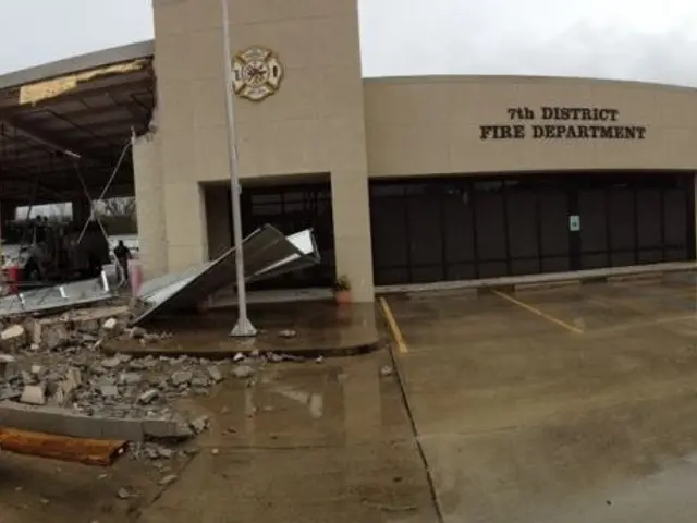 The image shows a building that has been torn down in the middle of a street, surrounded by...