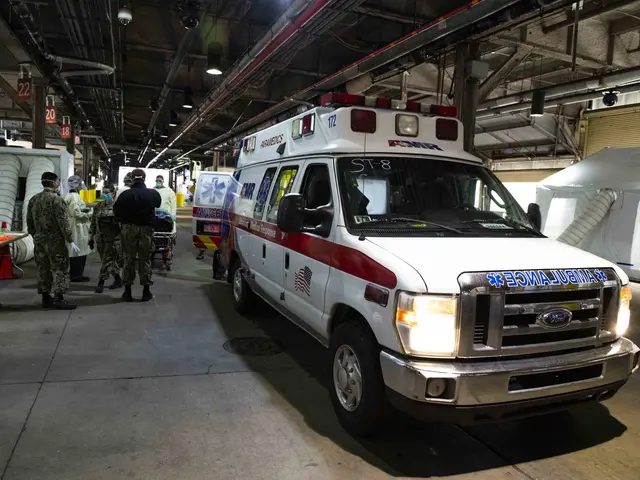 The image shows an ambulance parked inside of a building, surrounded by a group of people wearing...
