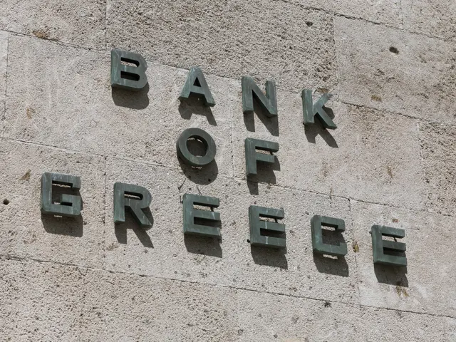 The image shows the Bank of Greece logo on the side of a building. The logo is written in bold...