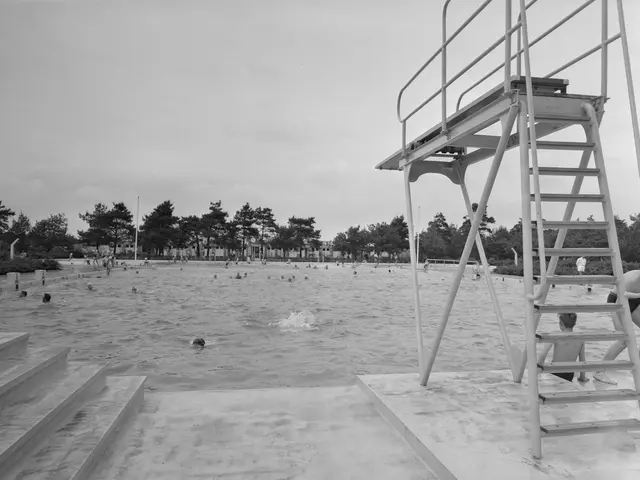The image shows a black and white photo of people swimming in the water at a beach, with a...