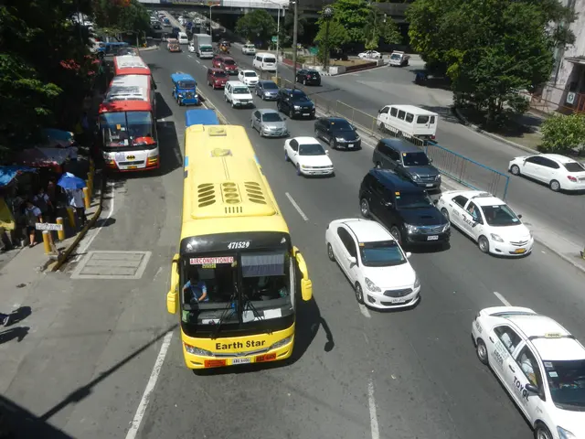 The image shows a busy street filled with lots of cars and buses, as well as people walking on the...