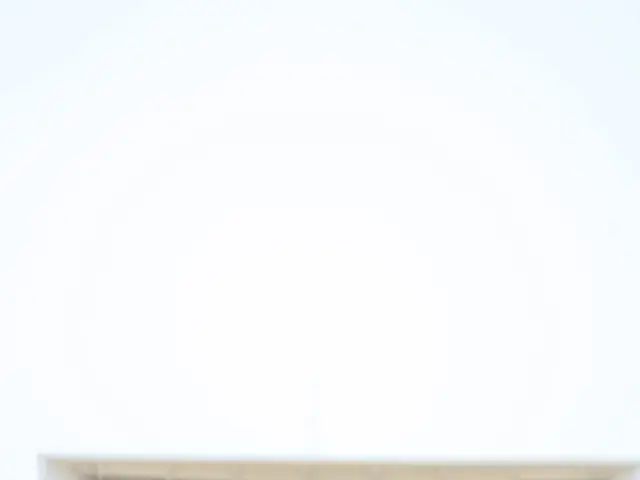 The image shows a small drone flying over a sandy beach next to a building, with the sky in the...