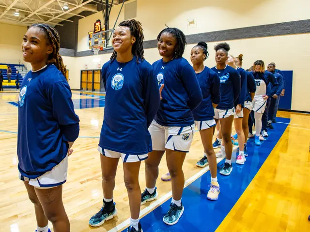The image shows a group of young women standing on top of a basketball court, wearing blue t-shirts...