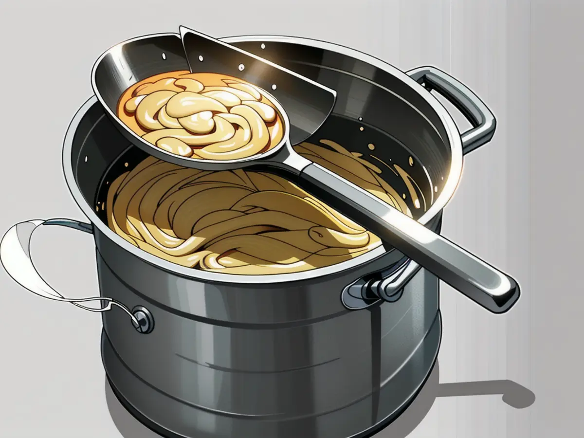 Strainer loaded with draining pasta empties over a cooking pot Pasta draining from strainer into pot above it