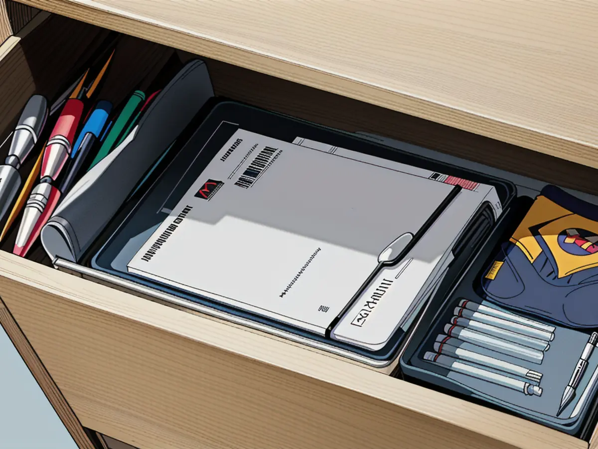 Peek inside a desk drawer, where mesh organizers neatly store pens, notebooks, paper clips, and assorted oddities. Laptop is semi-concealed above.
