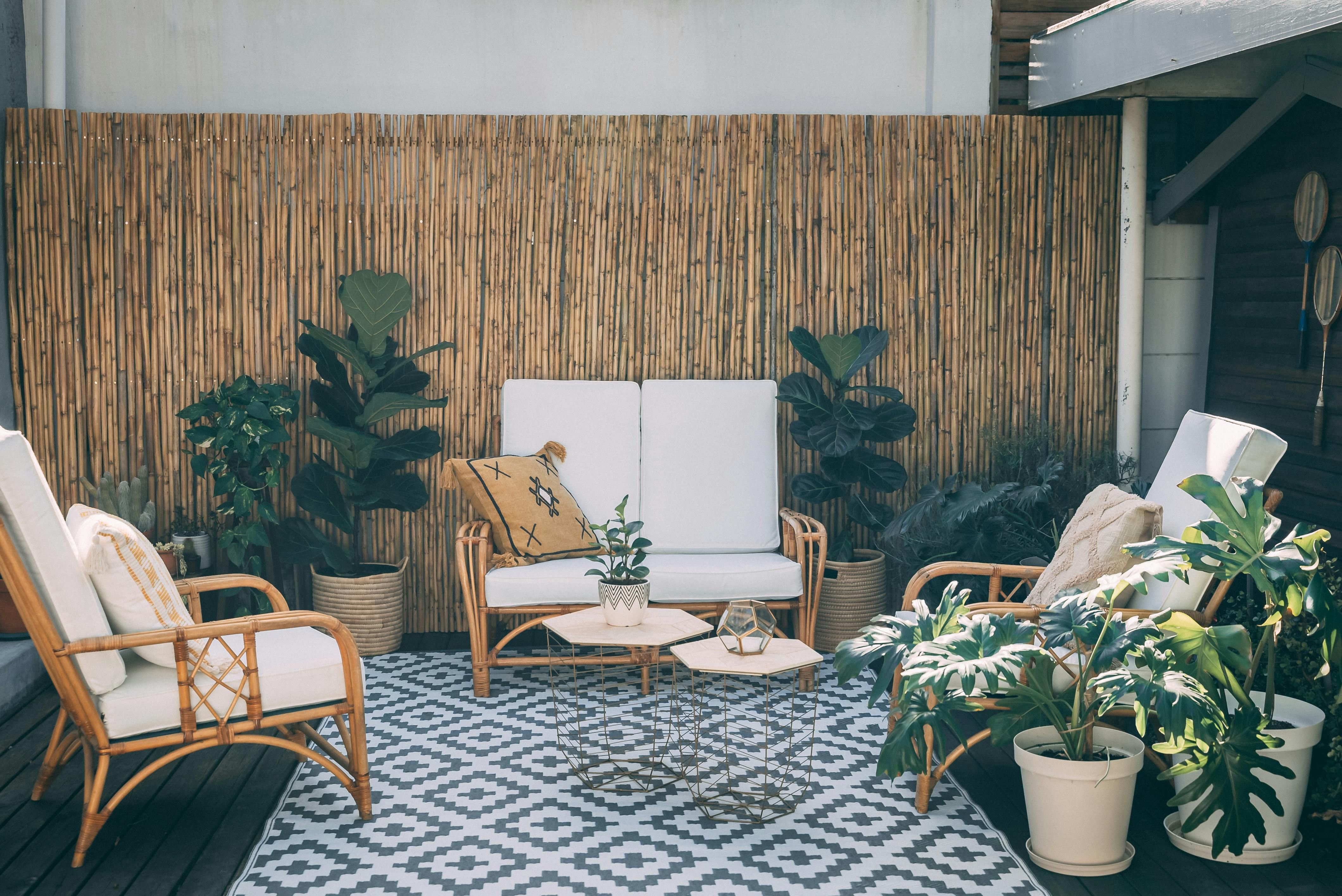 A patio adorned with wooden deck tiles offers a warm, plant-filled setting, ideal for drawing inspiration for outdoor retail concepts. Outdoor shopping space enhanced with wooden deck tiles, featuring blooming potted plants as surrounding decor, offering an inviting patio ambiance