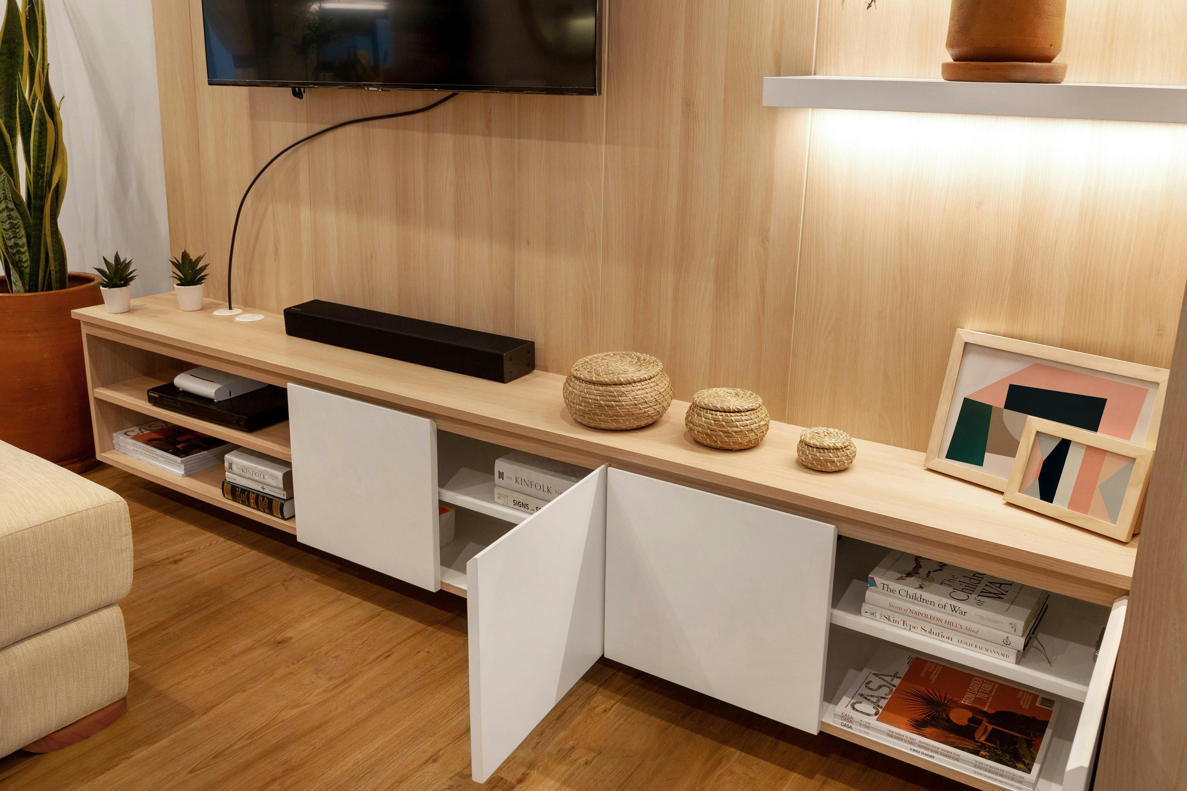 Shelf unit holding a television and containing various items placed inside it Shelf unit housing a TV and containing various items inside it.