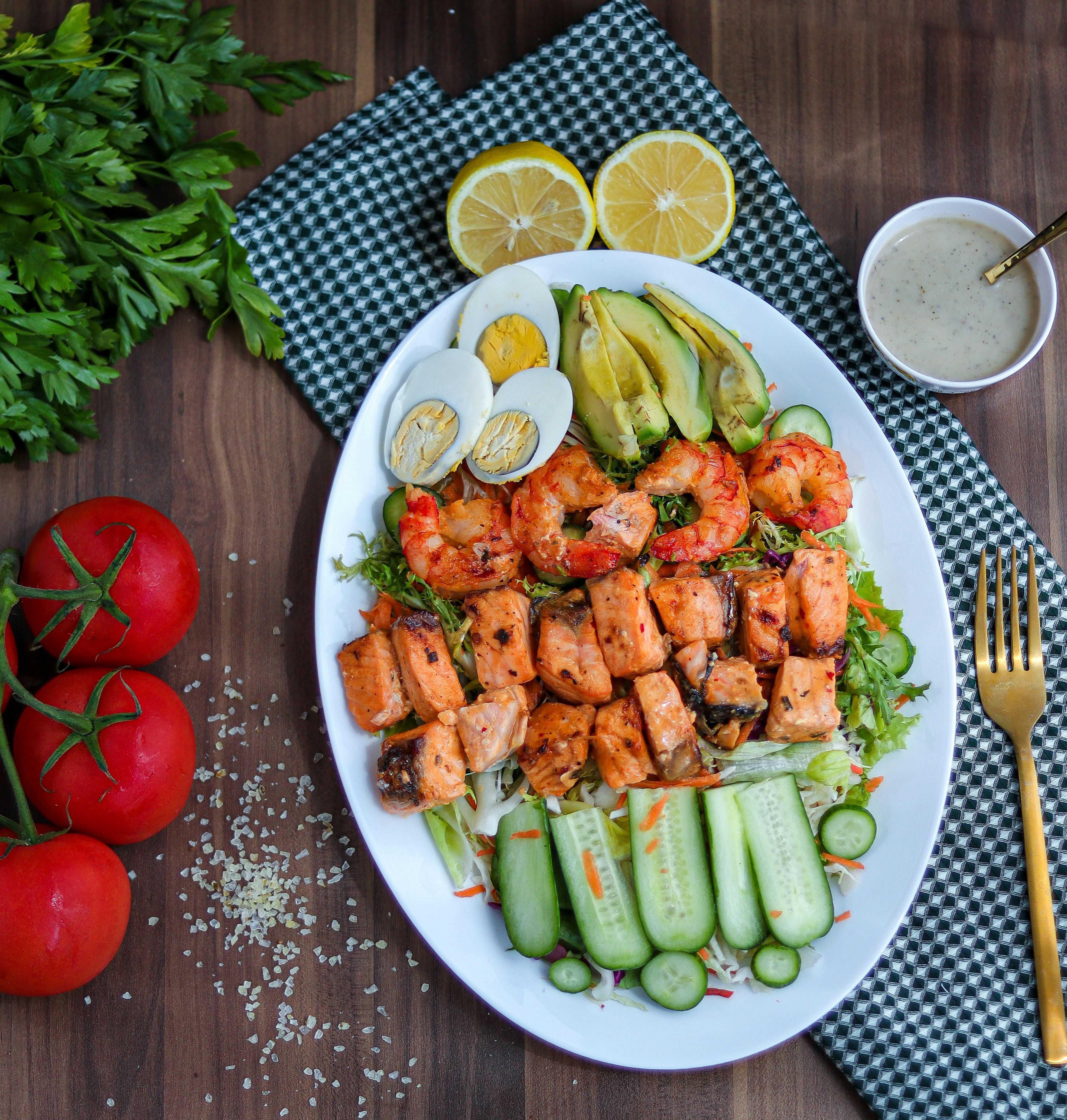 Dish featuring farro, grilled shrimp, kale, and grape tomatoes served on a bowl Dish featuring cooked farro, seared shrimp, kale, and halved cherry tomatoes on top