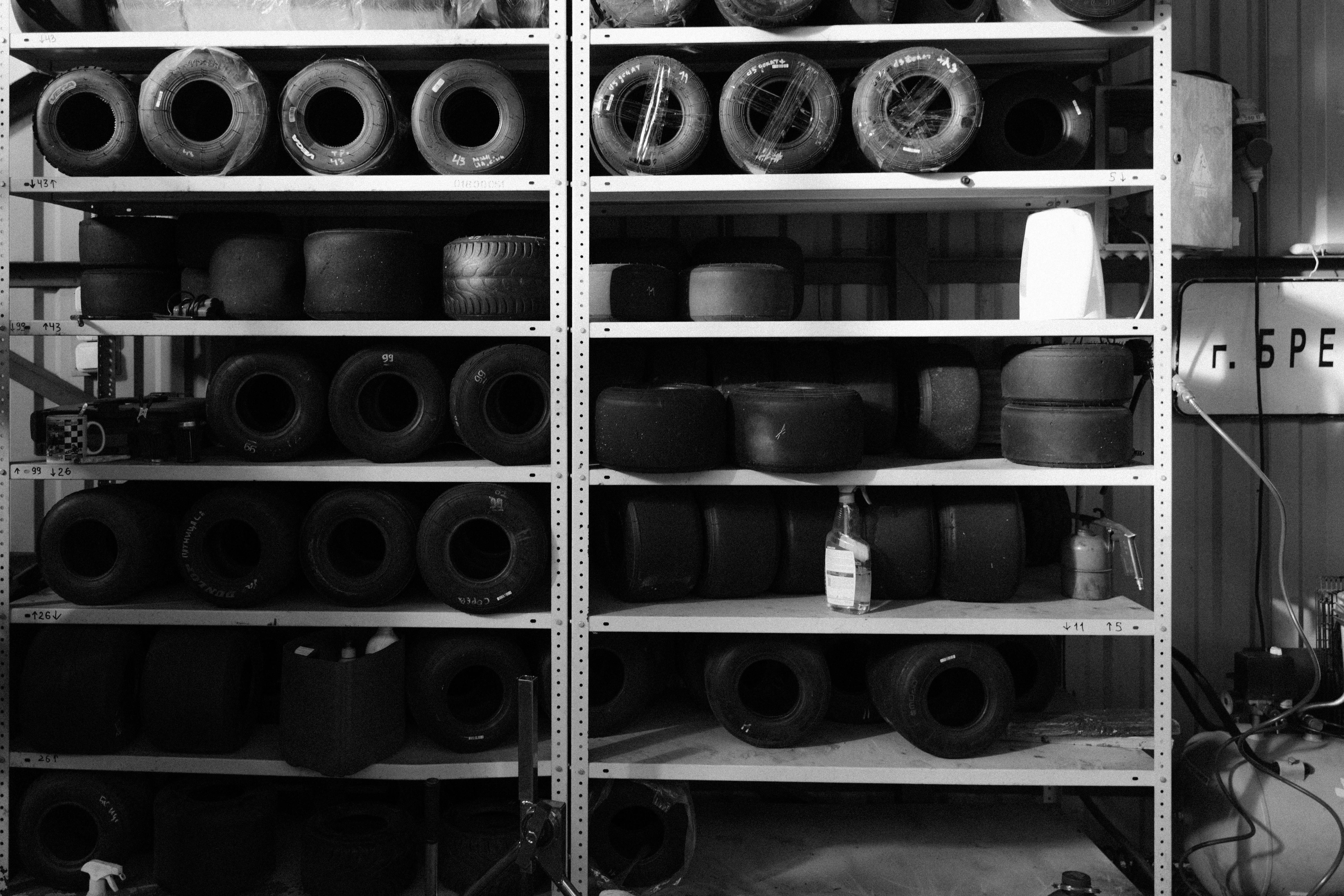 Examine the image of the garage shelving unit, filled with sporting goods and camping equipment. Investigate image of storage rack in garage filled with recreational sports and camping gear.