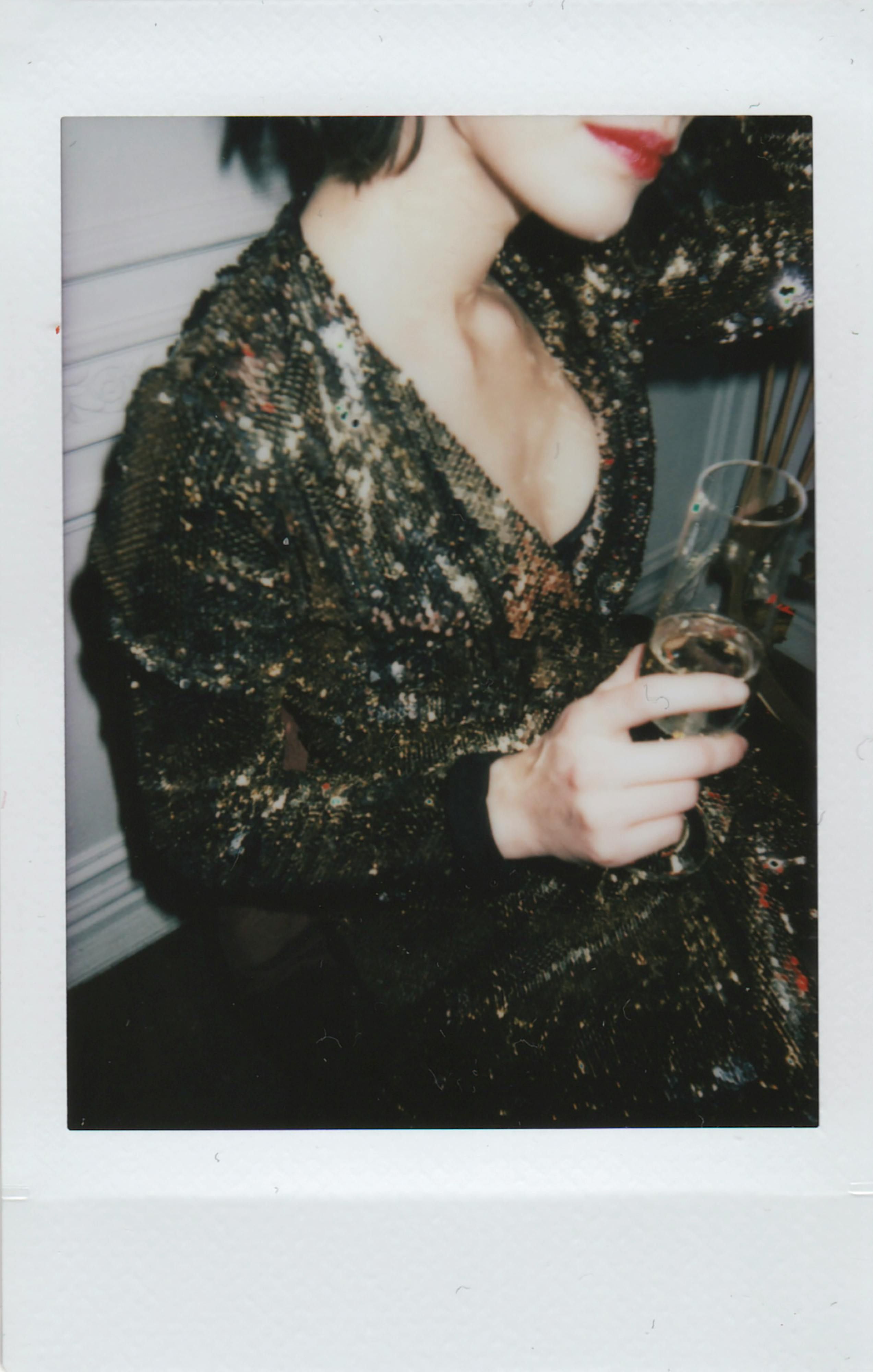 Model donning a gold sequined long-sleeved dress, featuring a short ruched wrap-front design. Gold-adorned model donning long-sleeved dress featuring sequins, completed with a brief, ruffled front wrap.