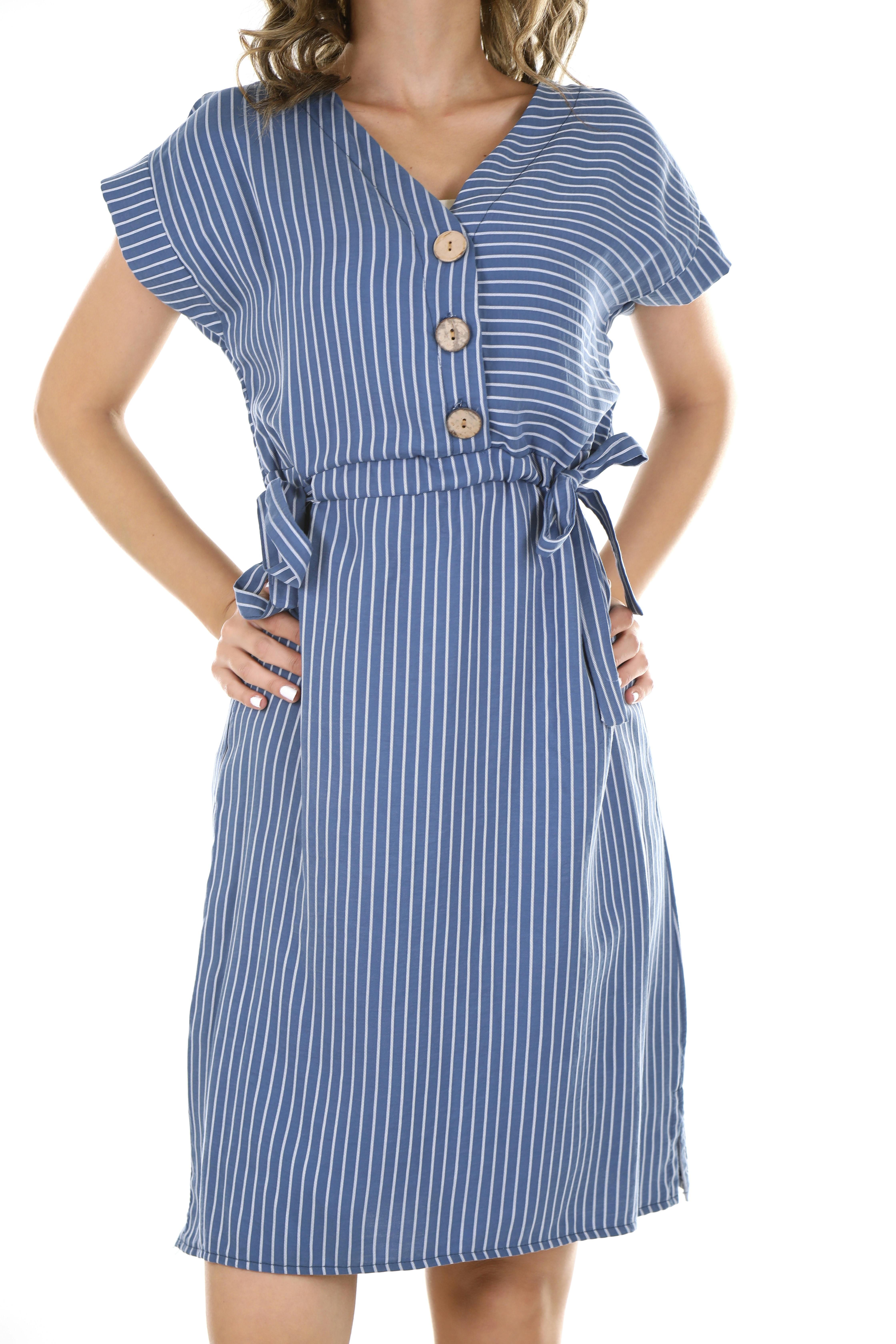Woman sporting a blue knit dress featuring a v-neck and voluminous long sleeves, down to her knees. Individual spotted wearing a v-neck, blue knee-length knit dress featuring voluminous long sleeves.