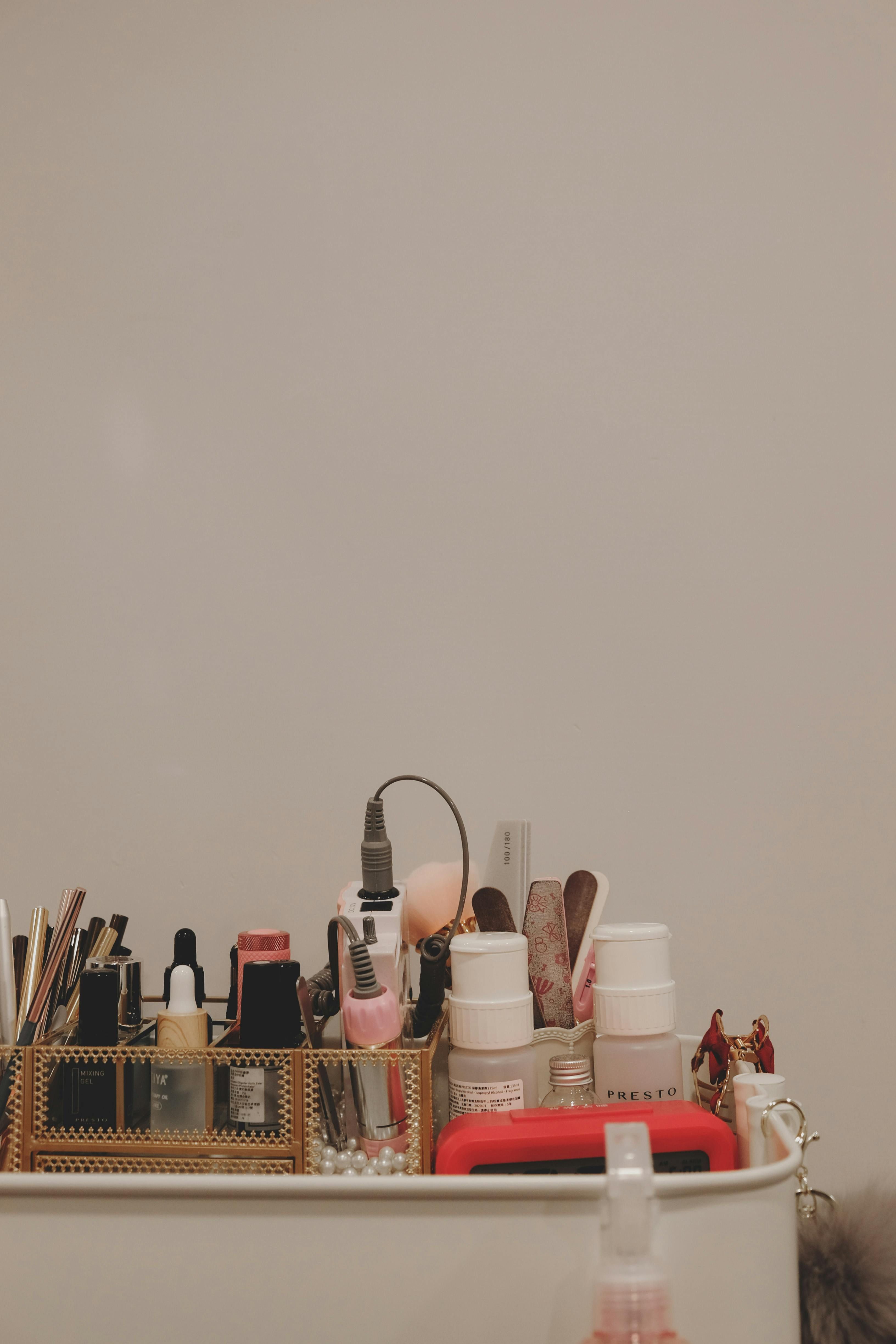 Disarrayed cosmetics stockpile fills the bathroom organizer, encompassing brushes, lipsticks, creams, et cetera. Stock bathroom cabinet overflowing with assorted cosmetics: brushes, lipsticks, creams, and so on.