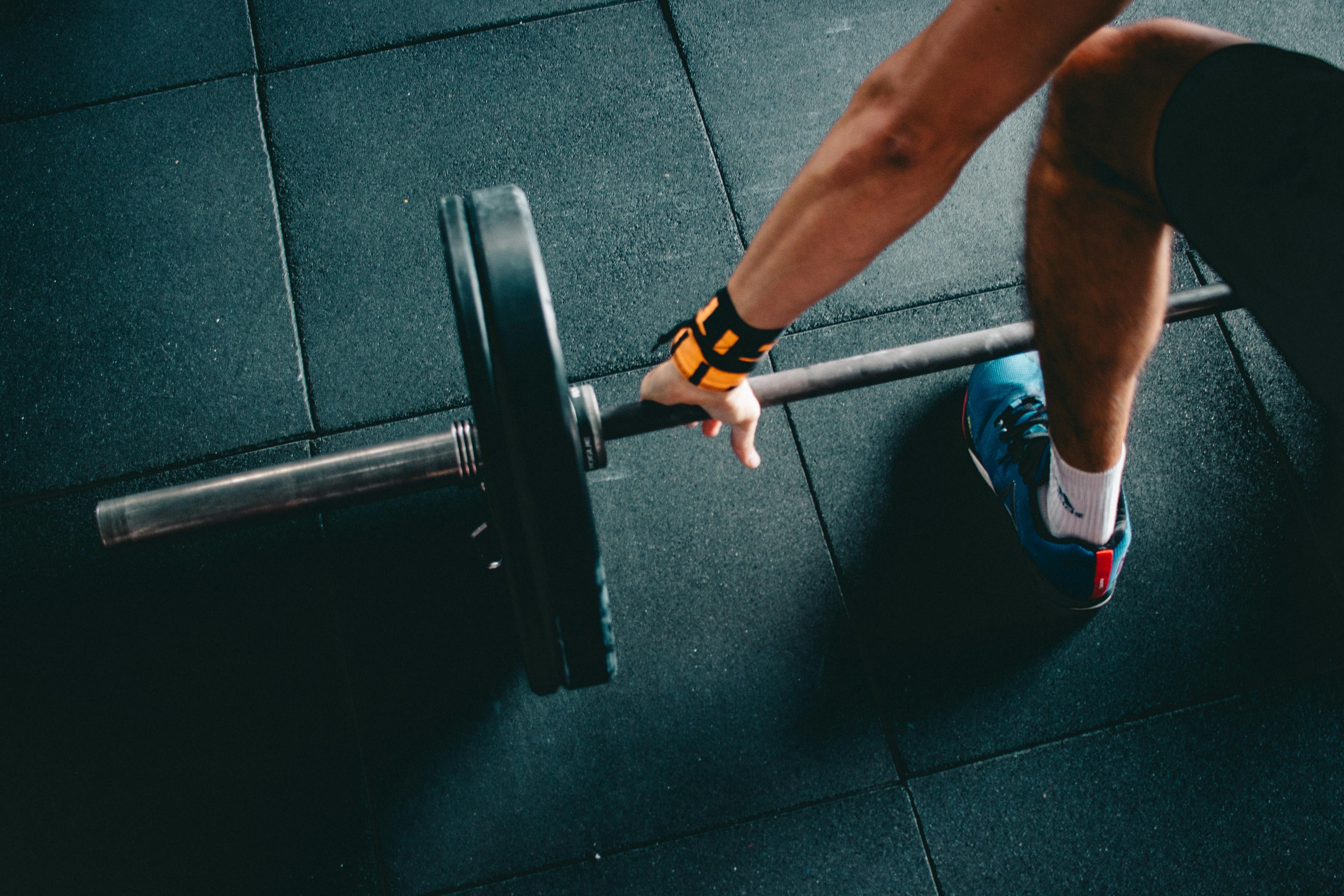 Exercise demonstration: Individual executing leg curl exercise, as depicted by a nearby reviewer and an exercise card. Exercise in progress: Leg curl demonstrated by the reviewer, with their hand positioned beside the fitness card.