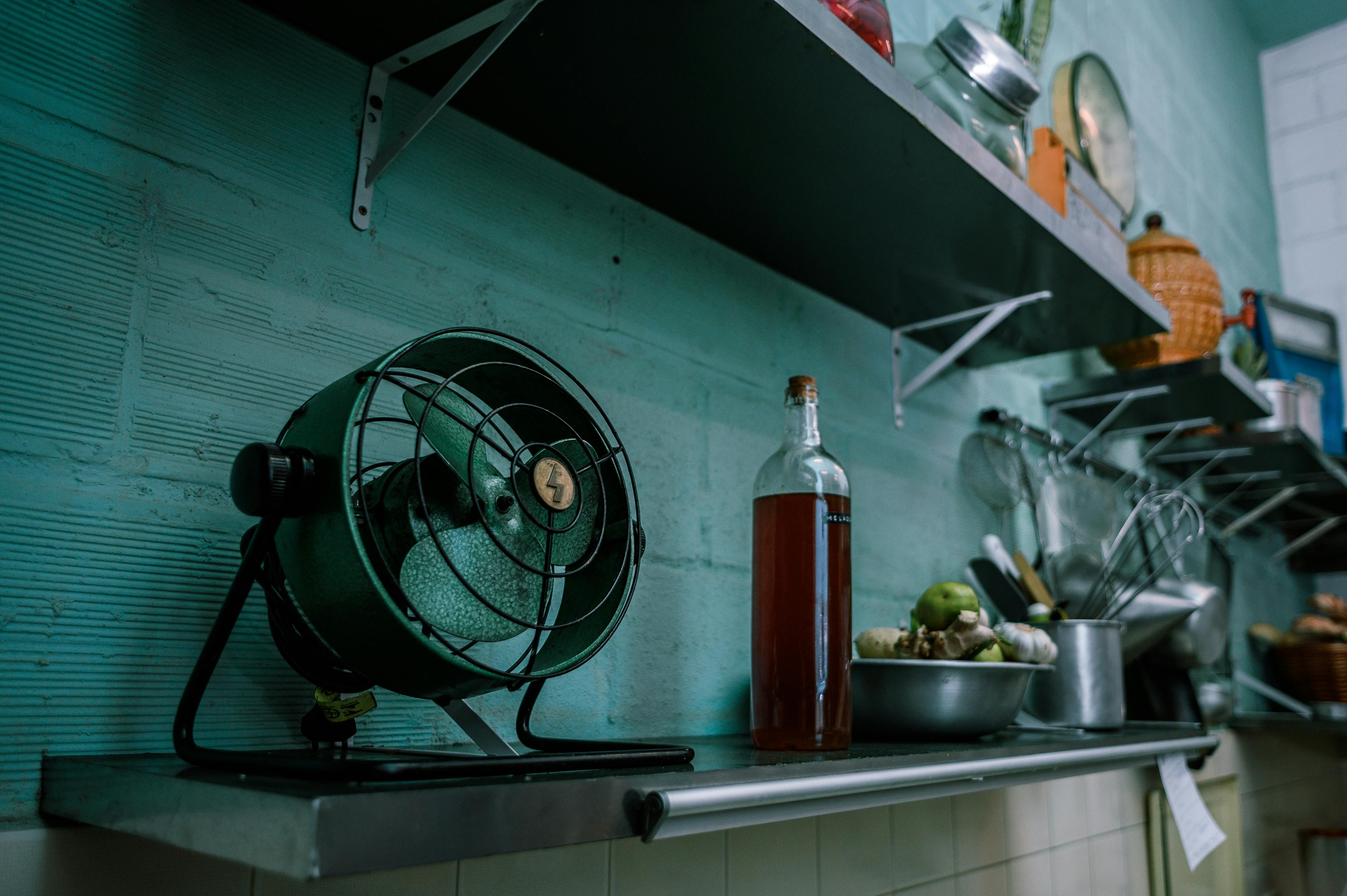 Kitchen counter houses a black stand fan Kitchen counter hosts a rotating black fan