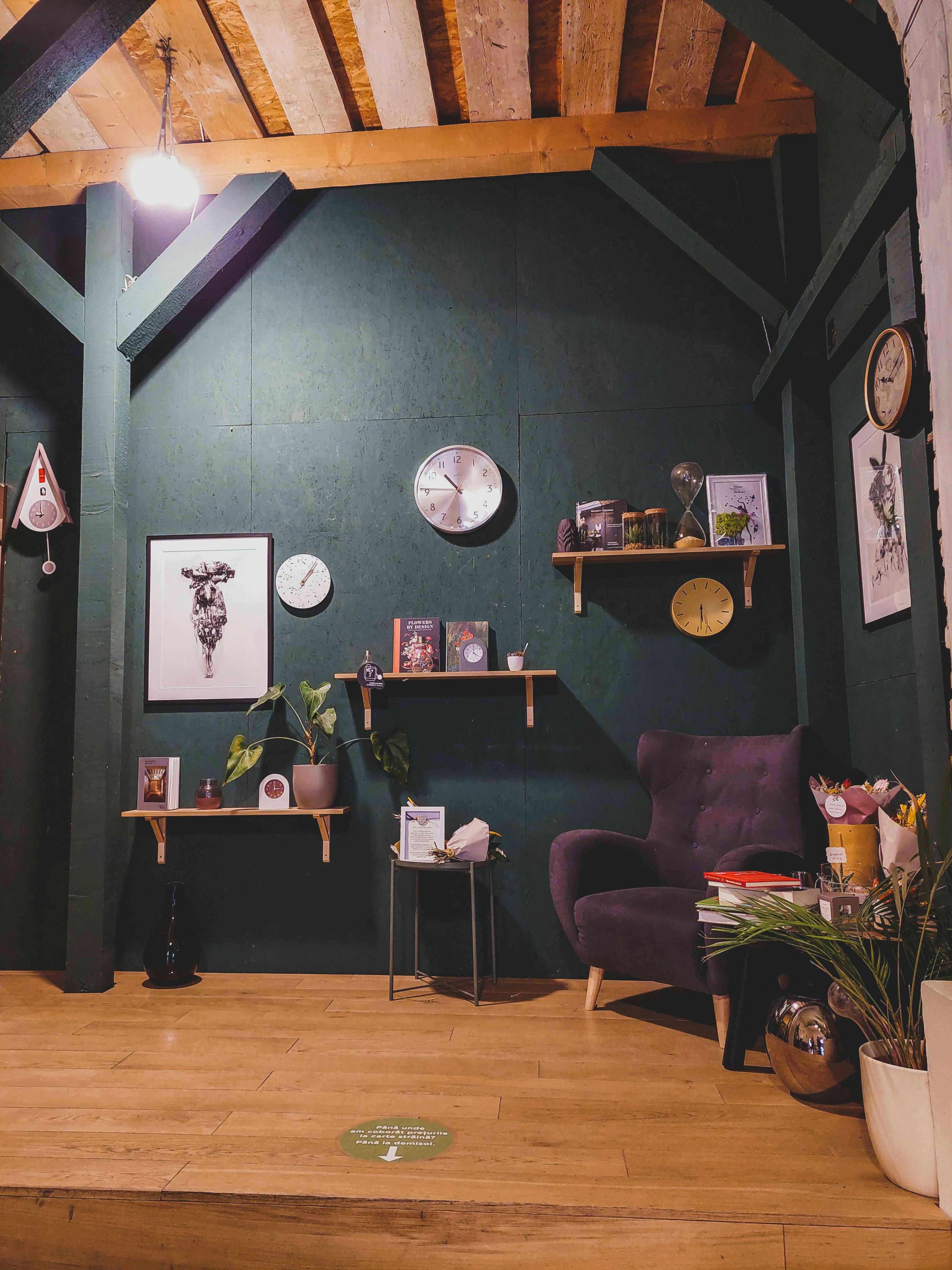 Comfortable green armchair and ottoman in a chic living space, complete with wooden side table and ornamented shelves. Comfortable, verdant armchair and accompanying footstool illuminate a fashionable living space, complete with a wooden side table and adorned shelving units.